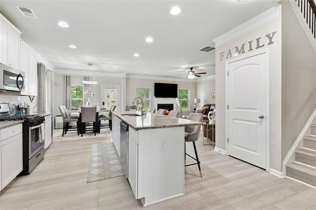 140 Canyons Ct, Hampton, GA 30228 - kitchen featuring appliances with stainless steel finishes, crown molding, ceiling fan, a kitchen breakfast bar, and plenty of natural light