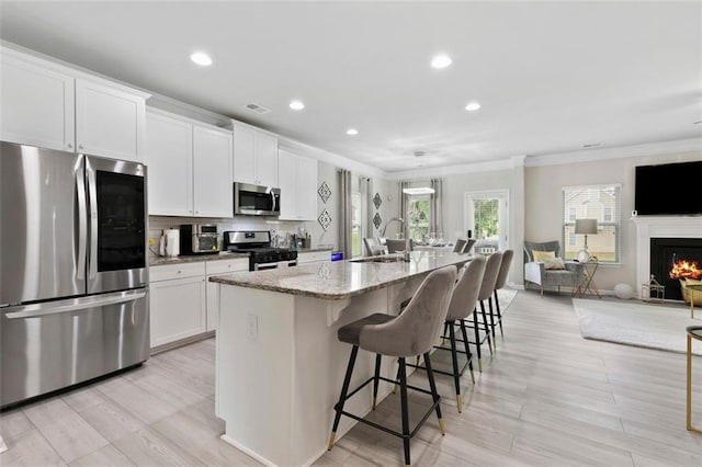 140 Canyons Ct, Hampton, GA 30228 - kitchen featuring stainless steel appliances, crown molding, a spacious island, a breakfast bar, and white cabinets