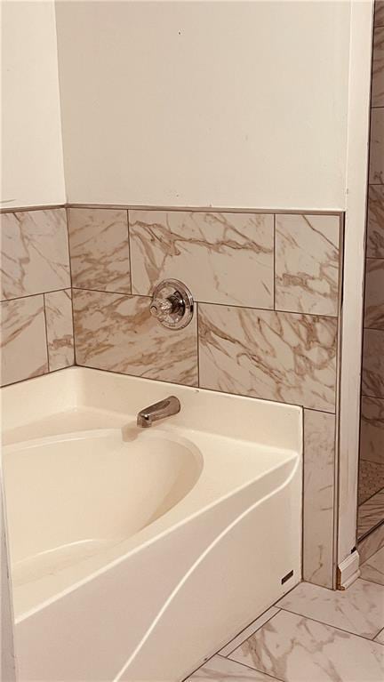 bathroom featuring a bath, marble finish floor, and wainscoting