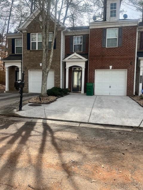 view of front of house with brick siding, a garage, and driveway