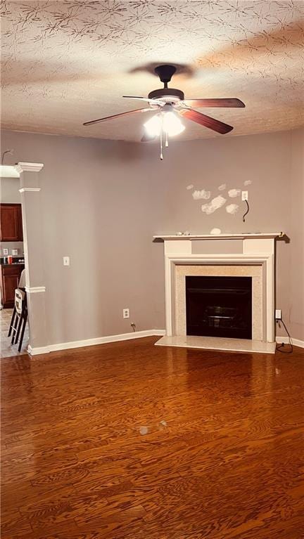 unfurnished living room featuring wood finished floors, a textured ceiling, ceiling fan, and a high end fireplace