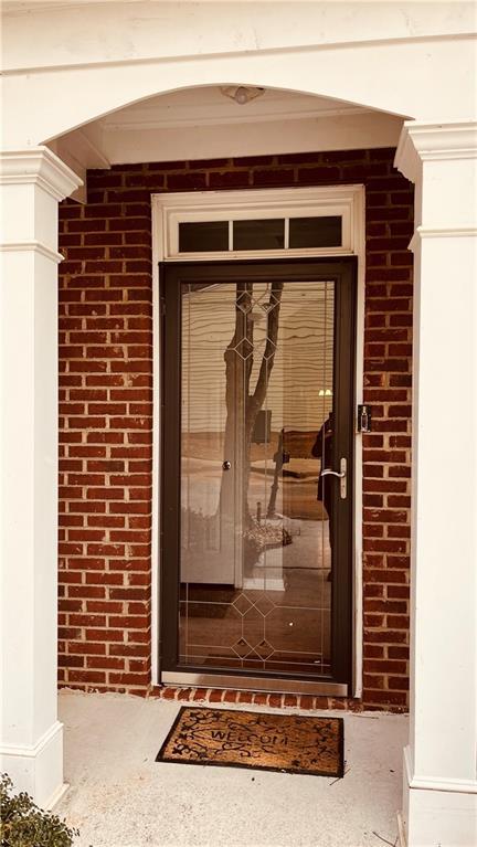 property entrance featuring brick siding and a porch