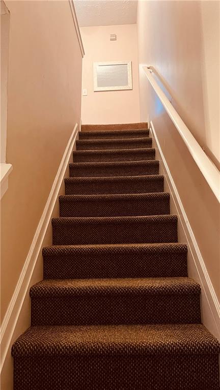 stairs featuring a textured ceiling