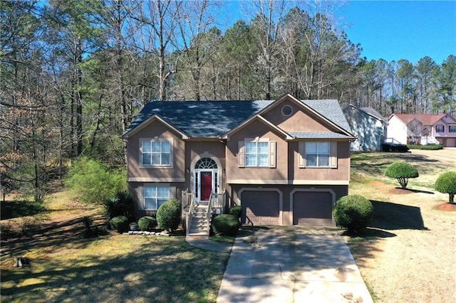 bi-level home featuring driveway, a garage, a front lawn, and stucco siding