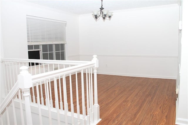 corridor featuring ornamental molding, baseboards, an inviting chandelier, and wood finished floors