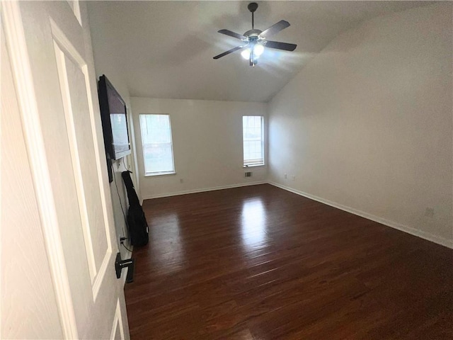 unfurnished room with a fireplace, a ceiling fan, baseboards, vaulted ceiling, and dark wood finished floors