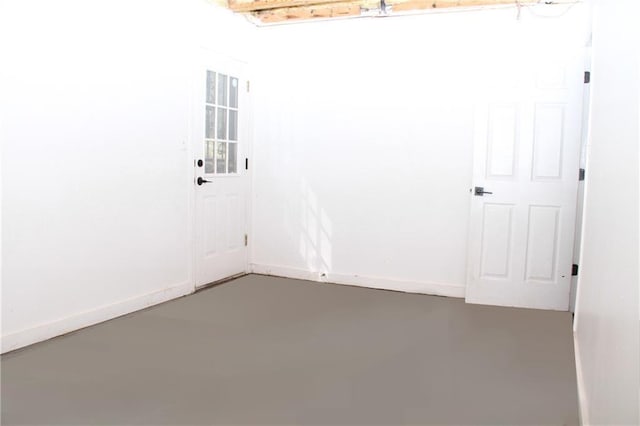 spare room featuring finished concrete floors and baseboards