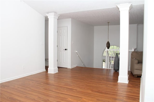 unfurnished room with light wood-style flooring, decorative columns, and baseboards