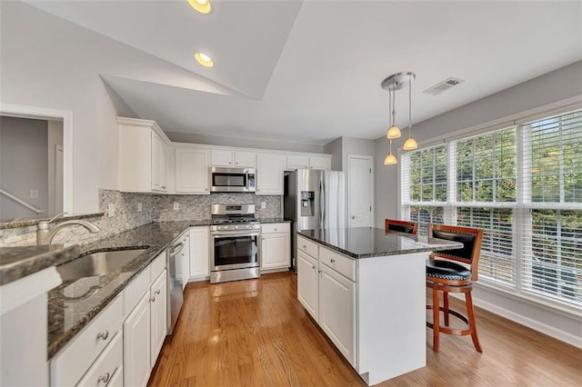 kitchen with a kitchen bar, appliances with stainless steel finishes, white cabinets, and a sink