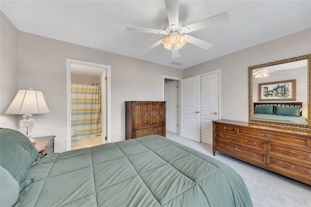 carpeted bedroom featuring ceiling fan, visible vents, and ensuite bathroom