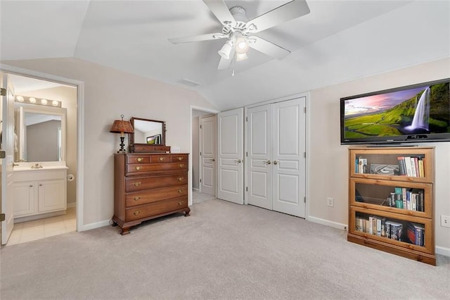 carpeted bedroom featuring lofted ceiling, a closet, ensuite bathroom, and baseboards