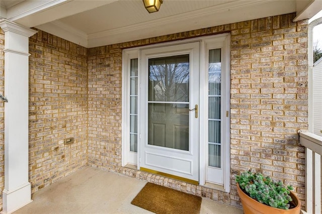 doorway to property with covered porch and brick siding