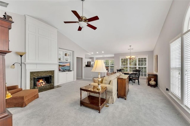 living area featuring light carpet, visible vents, a wealth of natural light, and a high end fireplace