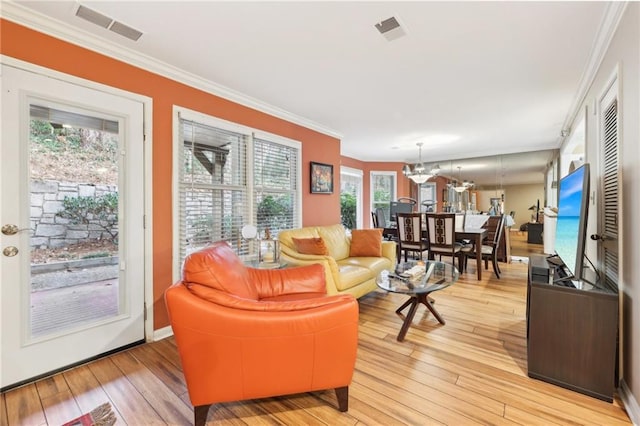 living room with a notable chandelier, light wood-type flooring, and ornamental molding