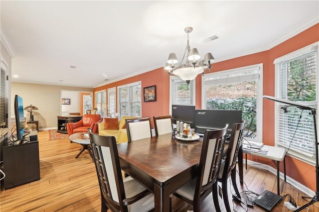 dining area with light hardwood / wood-style flooring, ornamental molding, and a notable chandelier