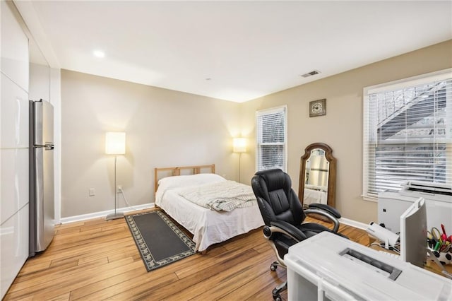 bedroom featuring light wood-type flooring and stainless steel refrigerator