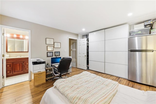 bedroom with ensuite bath, stainless steel fridge, sink, and light hardwood / wood-style flooring