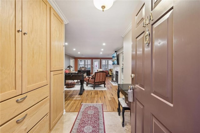 foyer entrance with light hardwood / wood-style flooring and crown molding