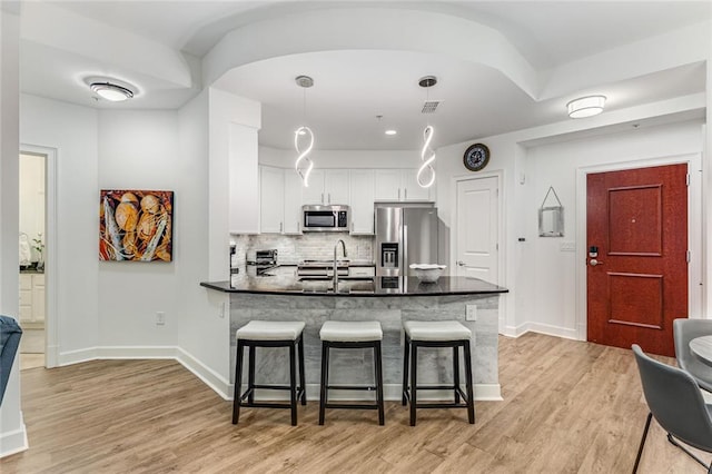 200 River Vista Dr Unit 713, Atlanta, GA 30339 - kitchen with a breakfast bar, a peninsula, white cabinetry, light wood-style floors, and appliances with stainless steel finishes