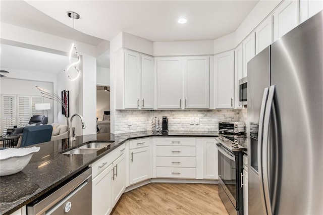 200 River Vista Dr Unit 713, Atlanta, GA 30339 - kitchen with light wood-style flooring, white cabinetry, dark stone counters, stainless steel appliances, and a sink