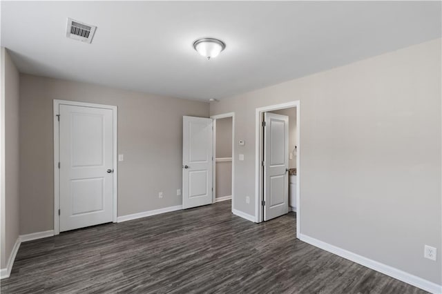 unfurnished bedroom with baseboards, visible vents, and dark wood-style floors