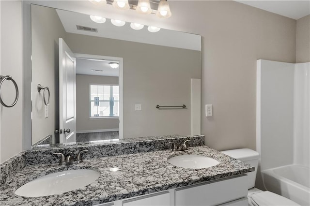 bathroom featuring toilet, a sink, visible vents, and double vanity