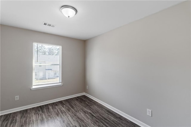 empty room with dark wood-style floors, baseboards, and visible vents