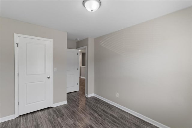 unfurnished bedroom with baseboards and dark wood-style floors