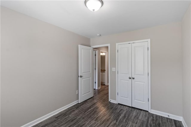 unfurnished bedroom with dark wood finished floors, a closet, and baseboards