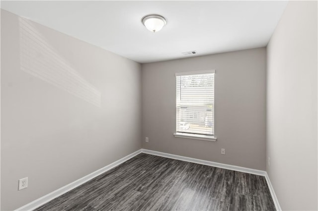 unfurnished room with baseboards, visible vents, and dark wood finished floors