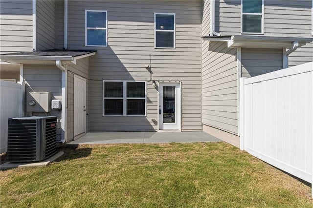 rear view of property featuring central air condition unit, a lawn, a patio, and fence