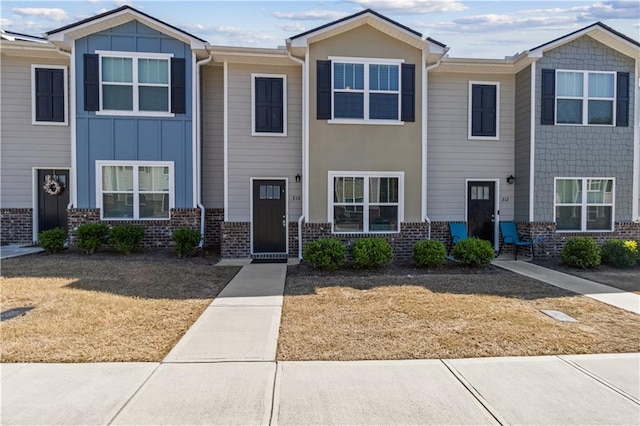 townhome / multi-family property featuring brick siding, board and batten siding, and a front yard