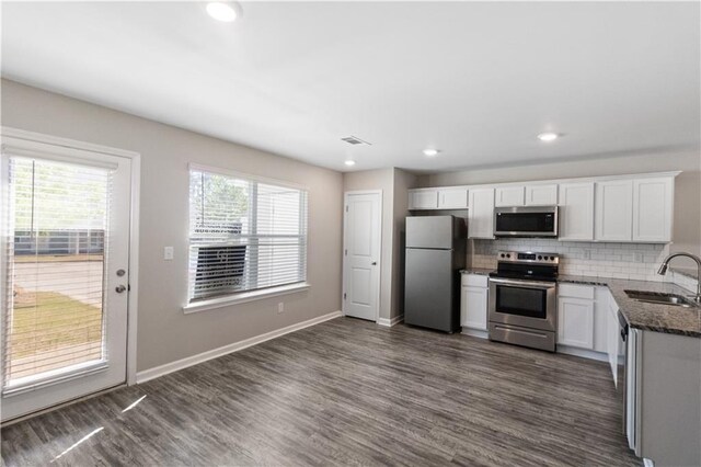 kitchen with a sink, appliances with stainless steel finishes, backsplash, dark wood-style flooring, and visible vents