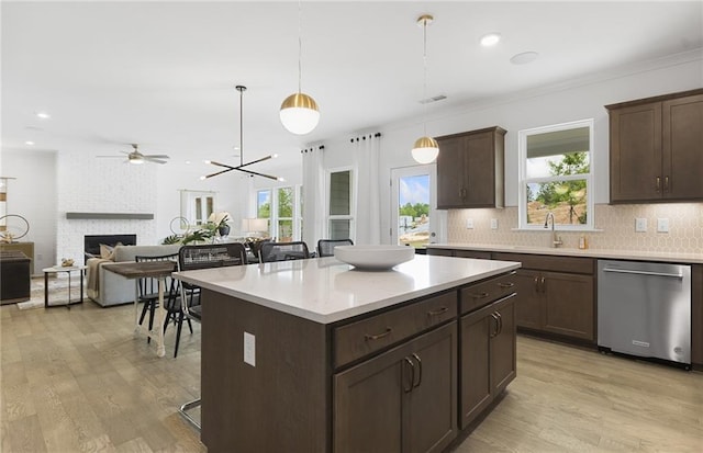 4317 Azalea Ridge Way, Hoschton, GA 30548 - kitchen featuring stainless steel dishwasher, a large fireplace, light wood-style flooring, dark brown cabinets, and ornamental molding