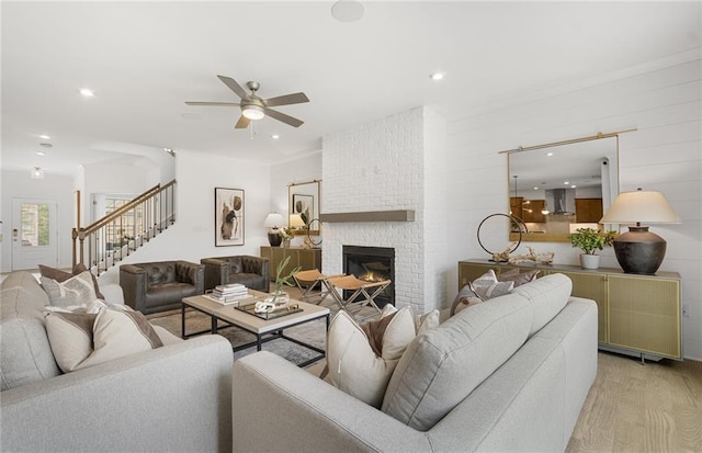 4317 Azalea Ridge Way, Hoschton, GA 30548 - living area featuring light wood finished floors, a ceiling fan, stairway, a brick fireplace, and recessed lighting