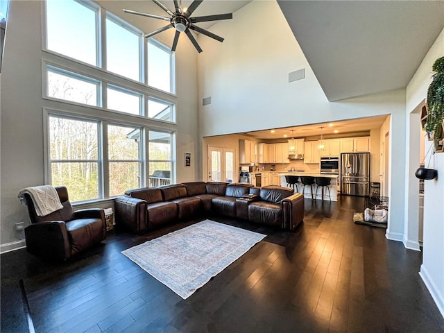 living room featuring dark hardwood / wood-style flooring, a towering ceiling, and ceiling fan