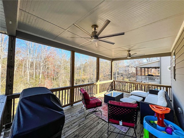 wooden terrace with an outdoor hangout area, grilling area, and ceiling fan