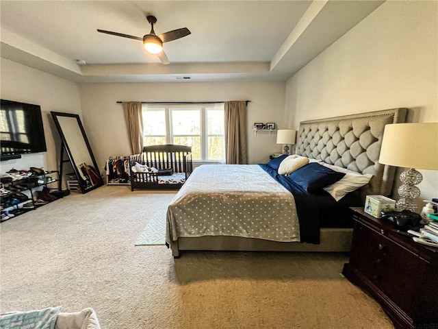 bedroom featuring carpet floors, a tray ceiling, and ceiling fan