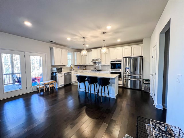 kitchen featuring white cabinetry, a center island, hanging light fixtures, and appliances with stainless steel finishes