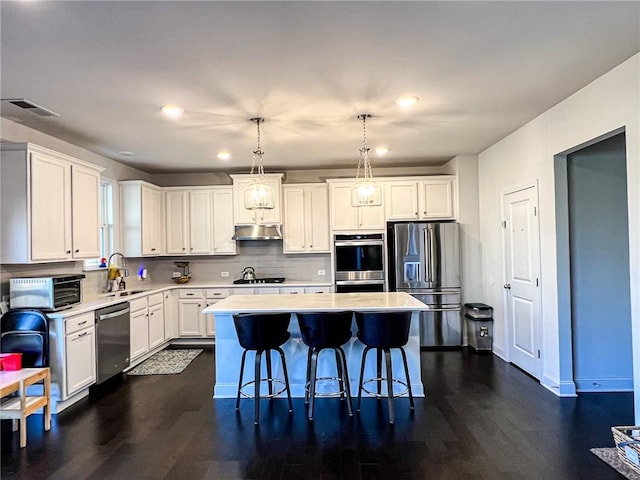 kitchen featuring white cabinetry, hanging light fixtures, a center island, and stainless steel appliances