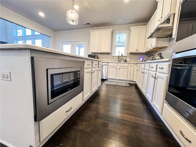 kitchen featuring backsplash, white cabinetry, dishwasher, oven, and hanging light fixtures