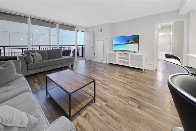 living area featuring visible vents, baseboards, and wood finished floors