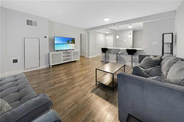 living area featuring baseboards, visible vents, and wood finished floors