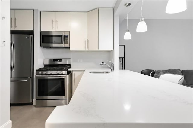 kitchen featuring a peninsula, appliances with stainless steel finishes, light countertops, and a sink