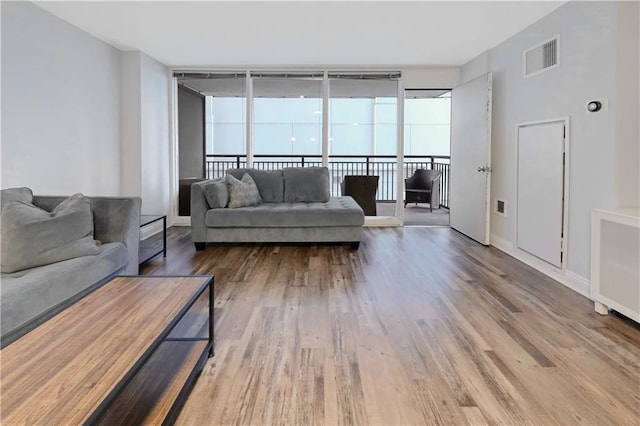 living area featuring baseboards, visible vents, and wood finished floors