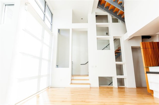 unfurnished living room featuring a towering ceiling and wood-type flooring