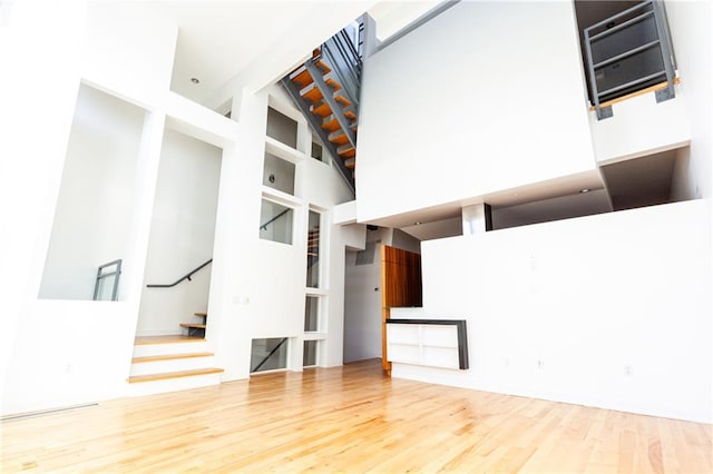 unfurnished living room with wood-type flooring and a towering ceiling