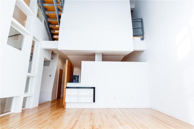 unfurnished living room featuring a high ceiling and light wood-type flooring