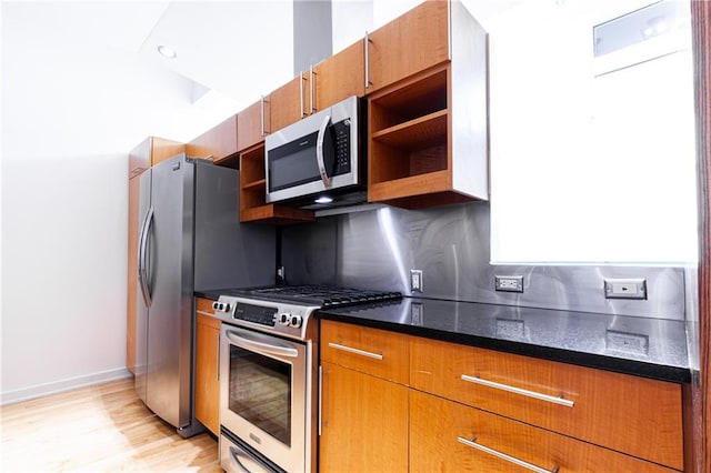 kitchen with stainless steel appliances, decorative backsplash, light hardwood / wood-style flooring, and dark stone counters