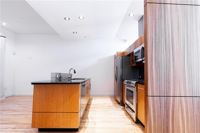 kitchen featuring appliances with stainless steel finishes, light hardwood / wood-style flooring, a kitchen island with sink, and sink